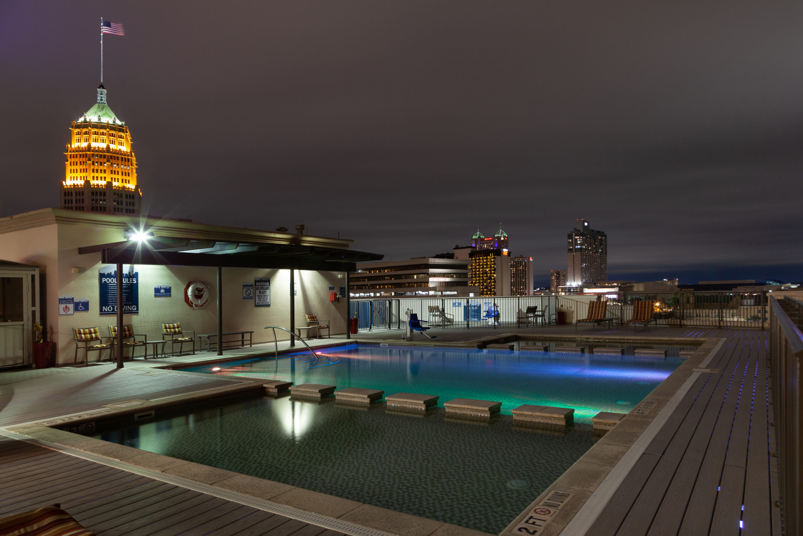 Wyndham La Cascada pool deck at night, lit water and city skyline beyond