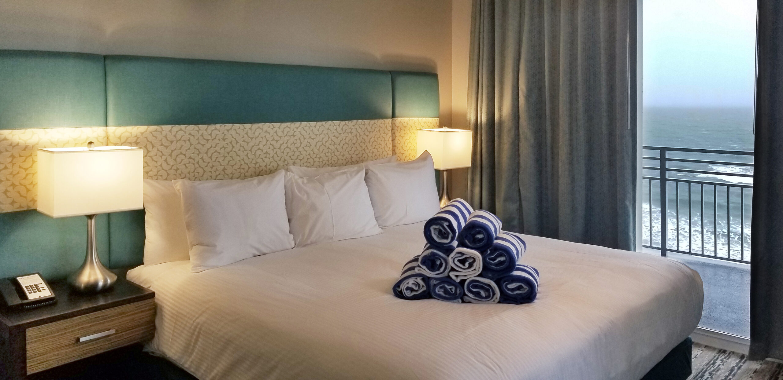 Oceanfront guestroom at Wyndham Ocean Walk with teal headboard and balcony access